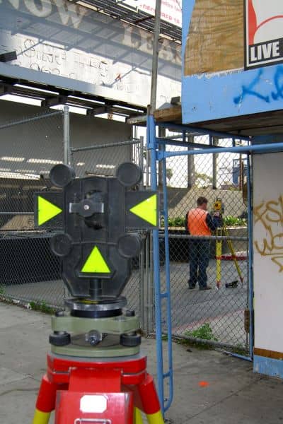 Licensed surveyor conducting boundary survey - ALTA SURVEY Florida Licensed land surveyor using precision equipment to conduct a boundary survey and mark accurate property lines for drainage and ownership clarity