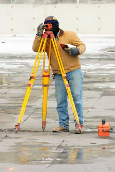 Licensed land surveyor using equipment to conduct a property survey and mark boundaries after erosion
