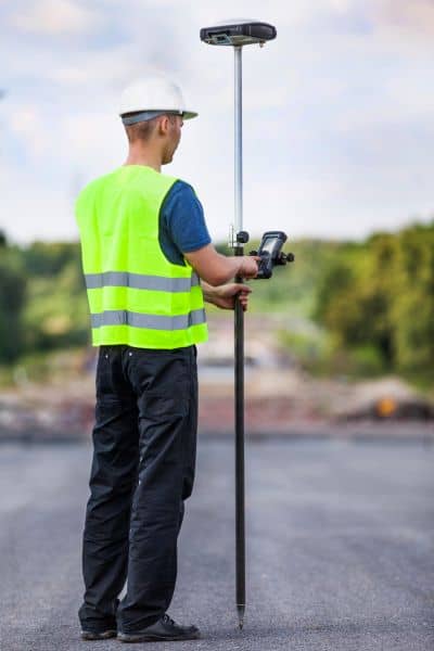 Land surveyor using GPS equipment to measure property elevation during a site survey.

