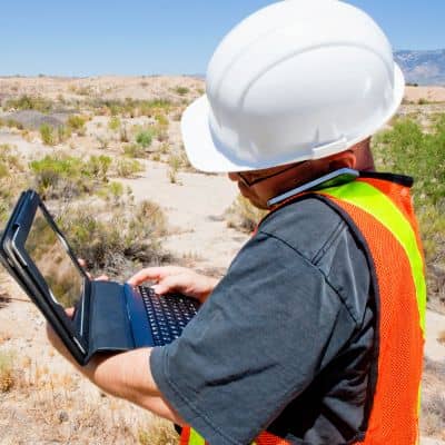 Land surveyor reviewing elevation data as part of topographic surveys to evaluate drainage patterns on a site