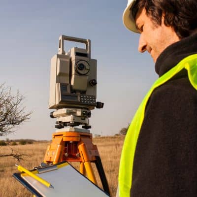 Licensed land surveyor documenting measurements during a property boundary survey in the field