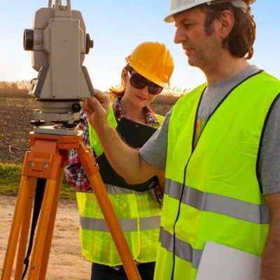Licensed land surveyor using field equipment to help homeowners find property lines
