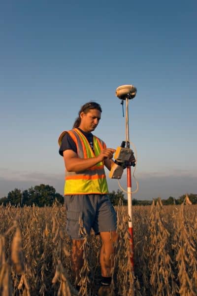 Land surveyor using GPS equipment to find property lines